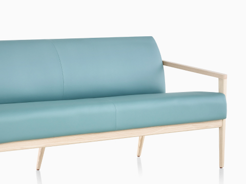 Three-quarter view of a teal Palisade Sofa with wood legs. our-values