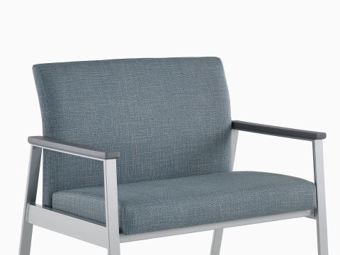 Front angle view of an Easton Plus Chair with blue upholstery, metallic four leg base, and slate grey arm caps. our-values