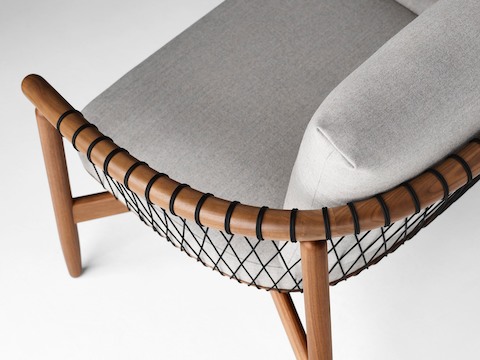 A detailed shot of a Crosshatch Settee with a walnut frame, black cords, and light neutral fabric. A detailed shot of a Crosshatch Settee with a walnut frame, black cords, and light neutral fabric.
