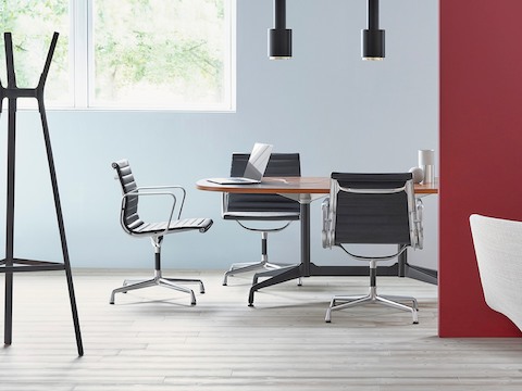Meeting room with black Eames Aluminum Group mid-back chairs around an Eames Table. Meeting room with black Eames Aluminum Group mid-back chairs around an Eames Table.