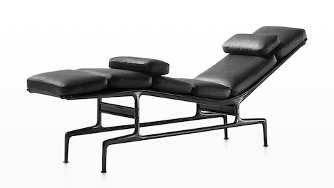 Angled view of a black leather Eames Chaise with a black frame and two additional loose cushions. Angled view of a black leather Eames Chaise with a black frame and two additional loose cushions.