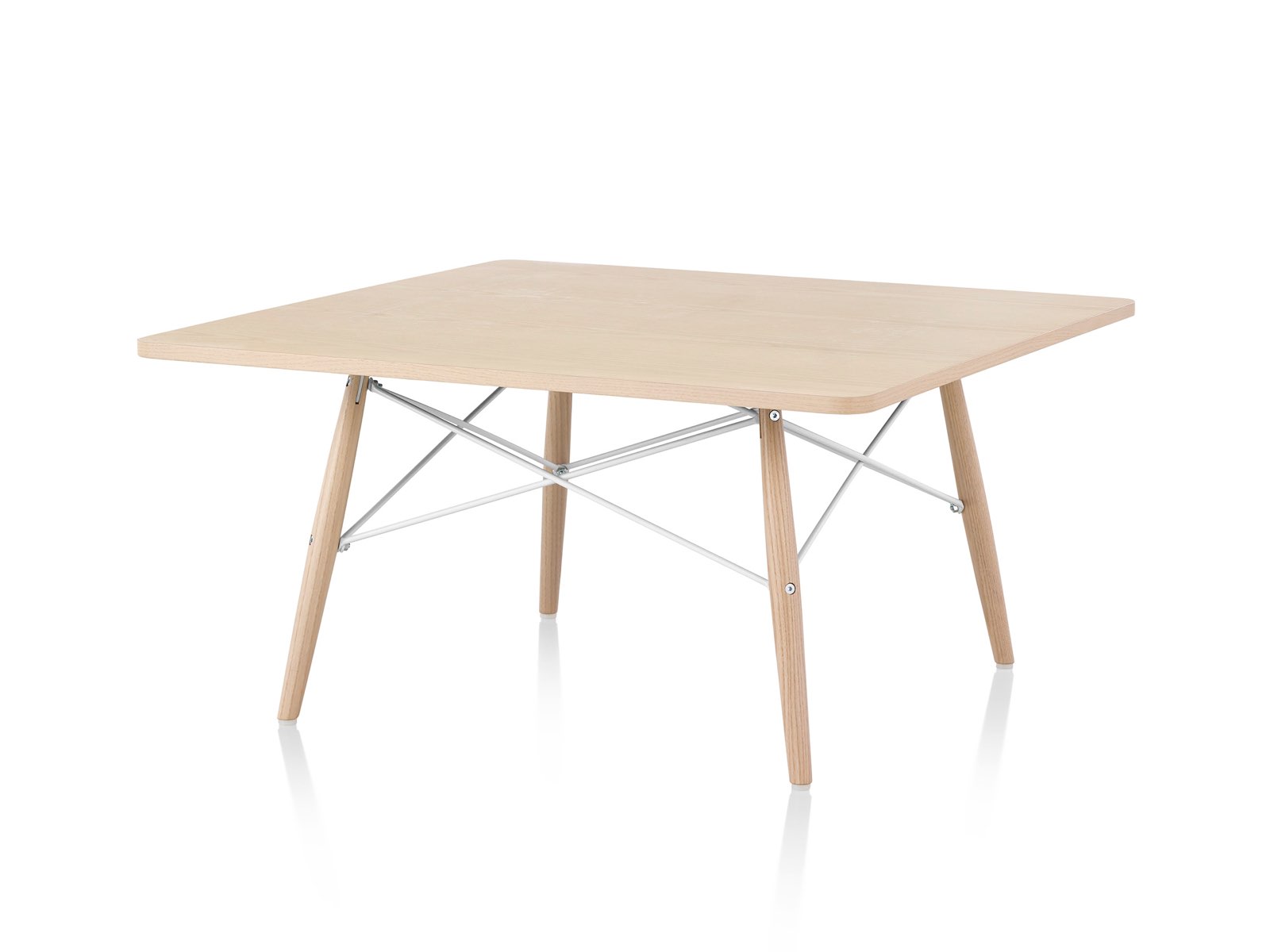 An angled view of an Eames Coffee Table with wood legs, metal cross-struts, and a light wood top. An angled view of an Eames Coffee Table with wood legs, metal cross-struts, and a light wood top.