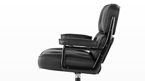 Profile view of a black leather Eames Executive Chair, showing the thickly cushioned seat, back, and arms. Profile view of a black leather Eames Executive Chair, showing the thickly cushioned seat, back, and arms.