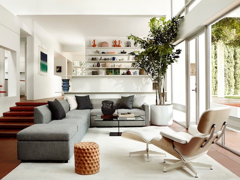 Three-quarter rear view of a white leather Eames Lounge Chair and Ottoman in a residential setting. Three-quarter rear view of a white leather Eames Lounge Chair and Ottoman in a residential setting.