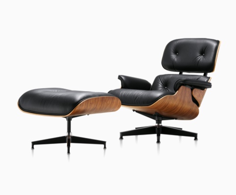 Black leather Eames Lounge Chair and Ottoman with a wood veneer shell, viewed from a 45-degree angle. Black leather Eames Lounge Chair and Ottoman with a wood veneer shell, viewed from a 45-degree angle.
