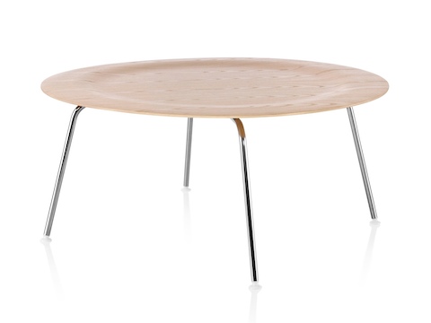 A round Eames Molded Plywood Coffee Table with metal legs and an indented top in a light finish. A round Eames Molded Plywood Coffee Table with metal legs and an indented top in a light finish.
