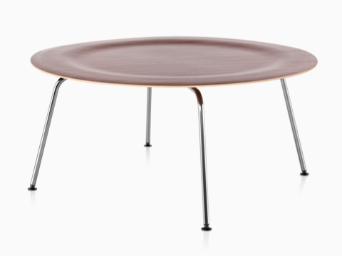 A round Eames Molded Plywood Coffee Table with metal legs and an indented top in a medium finish. A round Eames Molded Plywood Coffee Table with metal legs and an indented top in a medium finish.