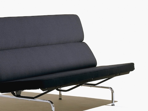 Angled view of a black Eames Sofa Compact, featuring the foam seat and back cushions and chrome-plated steel legs. Angled view of a black Eames Sofa Compact, featuring the foam seat and back cushions and chrome-plated steel legs.