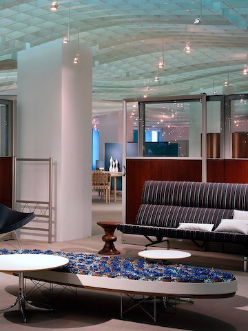 An Eames Wire Base Elliptical Table in an office lobby that also features an Eames Walnut Stool and Eames Sofa Compact. An Eames Wire Base Elliptical Table in an office lobby that also features an Eames Walnut Stool and Eames Sofa Compact.