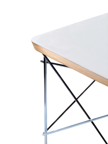 Partial view of a white Eames Wire Base Low Table, focusing on the welded wire rods and beveled top edge. Partial view of a white Eames Wire Base Low Table, focusing on the welded wire rods and beveled top edge.
