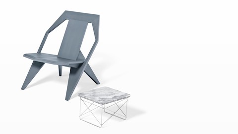 An Eames Wire Base Low outdoor table paired with a gray outdoor chair. An Eames Wire Base Low outdoor table paired with a gray outdoor chair.