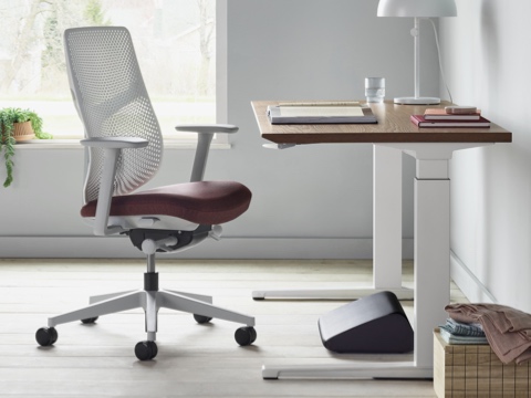 A side view of black Foot Pillow, under a Renew Sit-to-Stand Table with a Verus Chair. A side view of black Foot Pillow, under a Renew Sit-to-Stand Table with a Verus Chair.