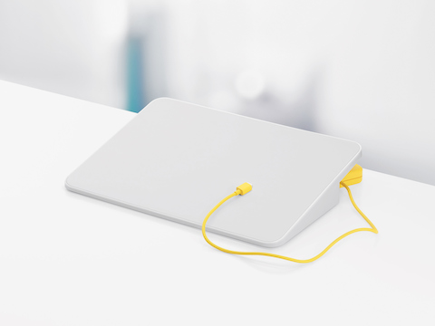 A white Formwork Media Stand and yellow charging cable. A white Formwork Media Stand and yellow charging cable.