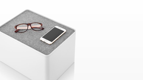 A white Formwork Tall Bin with a non-skid liner used as a lid, which holds glasses and a smartphone. A white Formwork Tall Bin with a non-skid liner used as a lid, which holds glasses and a smartphone.