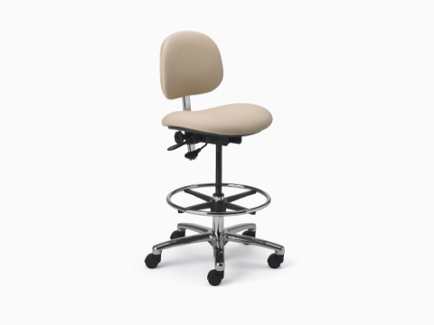 Lab Stool in a beige upholstered seat and back and a chrome base with dual lever adjustment, footrest, and a 5-star base with casters. Lab Stool in a beige upholstered seat and back and a chrome base with dual lever adjustment, footrest, and a 5-star base with casters.