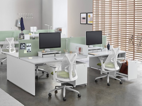 An office setting with two white, four-pack Layout Studio bench that has green fabric, center privacy screens, Sayl Chairs, and Tu Wood pedestals. An office setting with two white, four-pack Layout Studio bench that has green fabric, center privacy screens, Sayl Chairs, and Tu Wood pedestals.