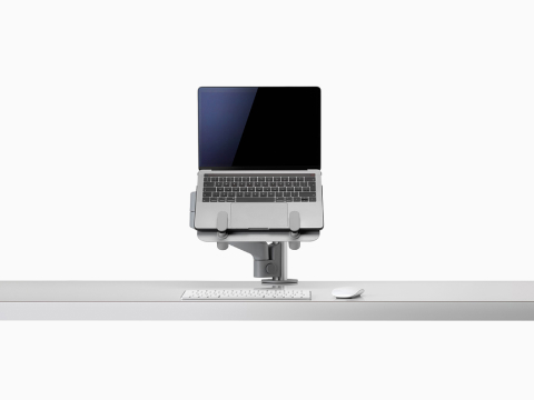 An open laptop raised from a desk and supported by a gray Lima Laptop Mount and Lima Monitor Arm. An open laptop raised from a desk and supported by a gray Lima Laptop Mount and Lima Monitor Arm.