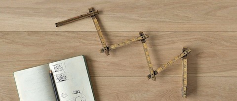 An overhead view of an antique folding ruler with a notebook and pencil on a wood surface. An overhead view of an antique folding ruler with a notebook and pencil on a wood surface.