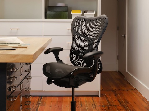 A Mirra 2 Stool with a Triflex back and adjustable arms in graphite by a storage table in a design studio. A Mirra 2 Stool with a Triflex back and adjustable arms in graphite by a storage table in a design studio.