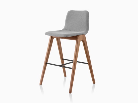 A gray upholstered NaughtOne Viv Wood Stool, viewed at an angle. A gray upholstered NaughtOne Viv Wood Stool, viewed at an angle.