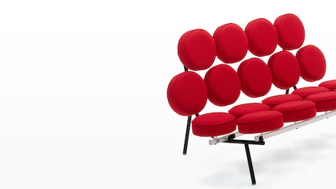A Nelson Marshmallow Sofa upholstered in red fabric, viewed from a 45-degree angle. A Nelson Marshmallow Sofa upholstered in red fabric, viewed from a 45-degree angle.
