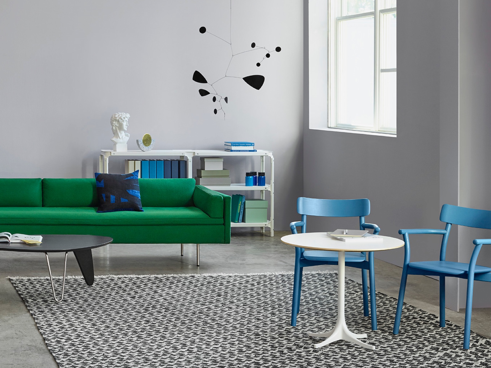 A white Nelson Pedestal Table accents a contemporary space featuring a green Bolster sofa. A white Nelson Pedestal Table accents a contemporary space featuring a green Bolster sofa.