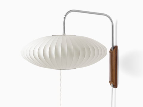 A Nelson Saucer Wall Sconce with a swivel arm and walnut wall mount. A Nelson Saucer Wall Sconce with a swivel arm and walnut wall mount.