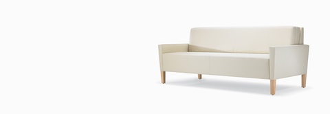 A three-quarter view of a Brava Flop Sofa in white textile with maple legs. A three-quarter view of a Brava Flop Sofa in white textile with maple legs.