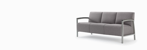 Front three-quarter view of a gray Brava Modern Lounge three-seat chair with wood arm caps. Front three-quarter view of a gray Brava Modern Lounge three-seat chair with wood arm caps.