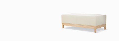 A three-quarter view of a Brava Platform Lounge Bench with maple base and white textile. A three-quarter view of a Brava Platform Lounge Bench with maple base and white textile.