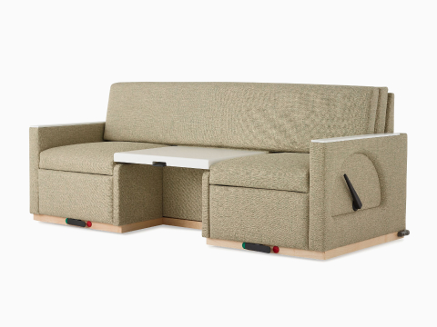 Angled view of a Nemschoff Merge 2 Flop Sofa in a beige upholstery with a white center table and a natural maple base. Angled view of a Nemschoff Merge 2 Flop Sofa in a beige upholstery with a white center table and a natural maple base.