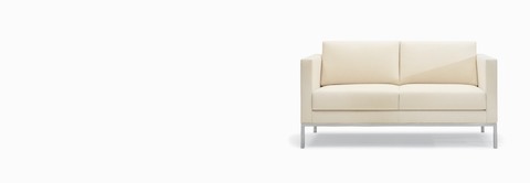 A Riva Sofa in a light-colored textile with brushed metal legs. A Riva Sofa in a light-colored textile with brushed metal legs.