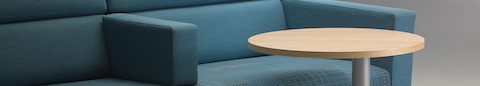 A close-up view of a Nemschoff Steps Lounge System in blue textile and a Steps round end table with a powder-coated base and laminate top. A close-up view of a Nemschoff Steps Lounge System in blue textile and a Steps round end table with a powder-coated base and laminate top.