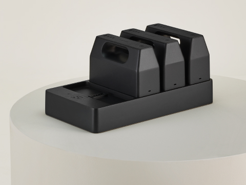 Three black OE1 Power Pack batteries docked on a black OE1 Power Tray, viewed from an angle. Three black OE1 Power Pack batteries docked on a black OE1 Power Tray, viewed from an angle.