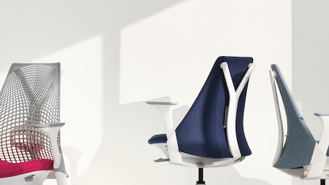 Three Sayl office chairs, one white with suspension back, one blue with upholstered back, and one light gray with upholstered back. Three Sayl office chairs, one white with suspension back, one blue with upholstered back, and one light gray with upholstered back.