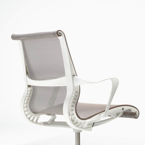 A rear-angle view of a Setu chair with fixed arms, a studio white frame, silver alloy base, and cocoa brown suspension. A rear-angle view of a Setu chair with fixed arms, a studio white frame, silver alloy base, and cocoa brown suspension.