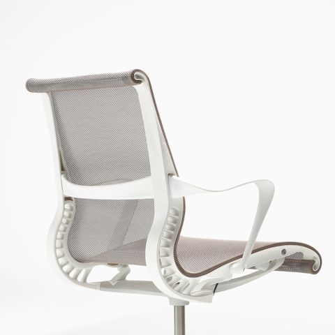 Rear-angle view of a Setu chair with fixed arms, a studio white frame, silver alloy base, and cocoa brown suspension. Rear-angle view of a Setu chair with fixed arms, a studio white frame, silver alloy base, and cocoa brown suspension.