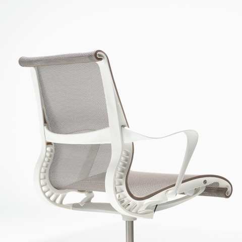 Rear-angle view of a Setu chair with fixed arms, a studio white frame, silver alloy base, and cocoa brown suspension. Rear-angle view of a Setu chair with fixed arms, a studio white frame, silver alloy base, and cocoa brown suspension.