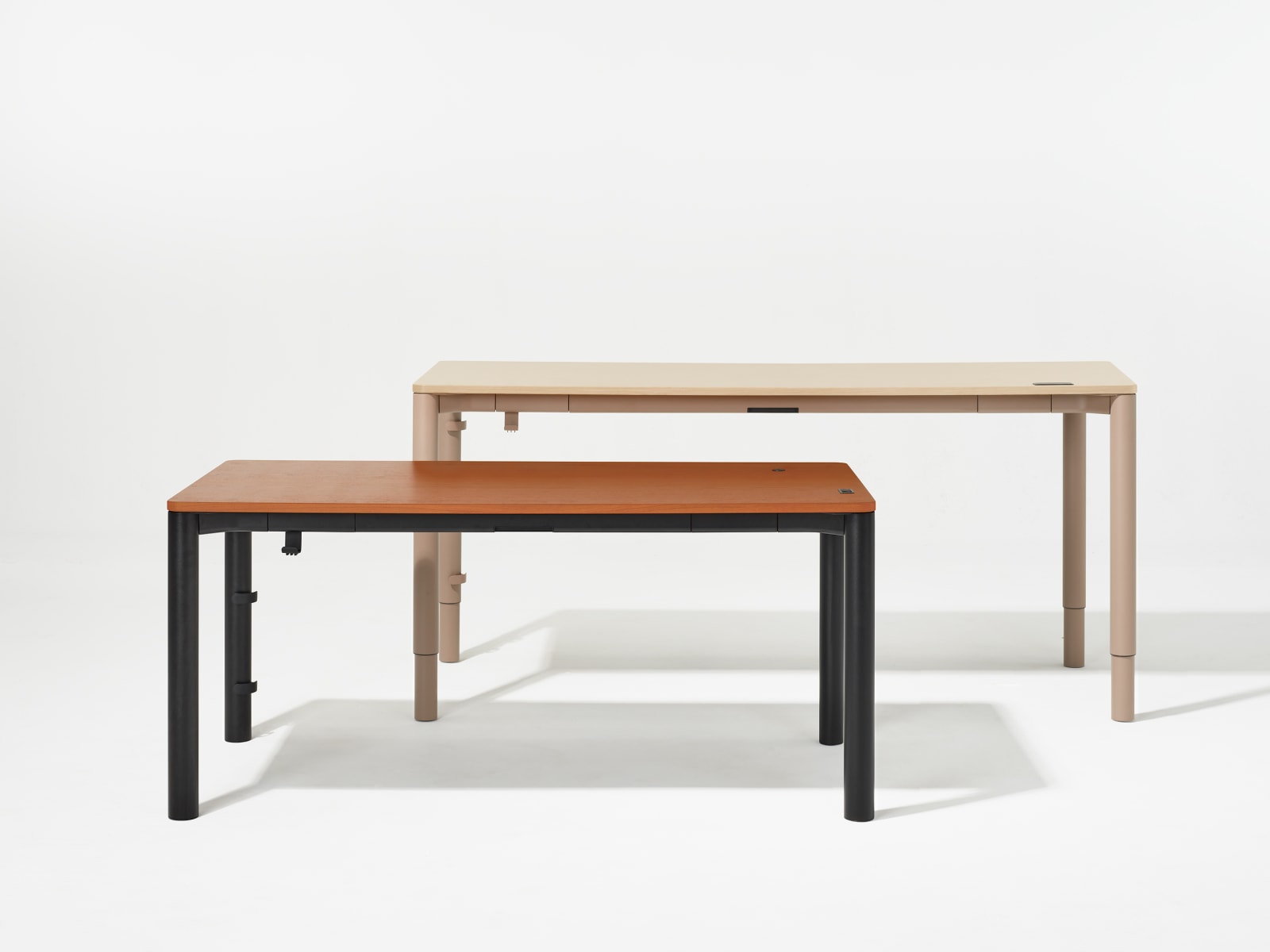 Two four leg height adjustable tables, one with a dark woodgrain surface and black legs and other with a light woodgrain surface and light brown legs shown at standing posture. Two four leg height adjustable tables, one with a dark woodgrain surface and black legs and other with a light woodgrain surface and light brown legs shown at standing posture.