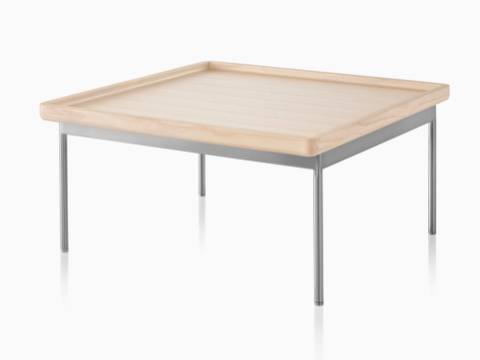 An angled view of a rectangular Tuxedo Table with a light woodgrain finish and silver metal base. An angled view of a rectangular Tuxedo Table with a light woodgrain finish and silver metal base.
