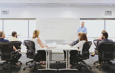 Employees sit in Aeron chairs and listen to a presentation inside of a meeting room. Employees sit in Aeron chairs and listen to a presentation inside of a meeting room.
