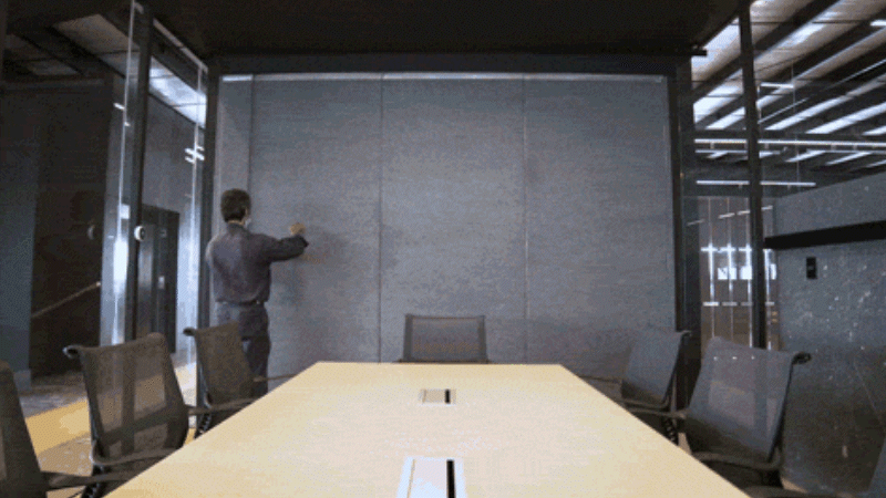 Brinco's employee adjusting panels to make the meeting room smaller. Brinco's employee adjusting panels to make the meeting room smaller.
