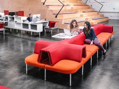 People work and discuss projects while seated at a desk and lounge sofas. People work and discuss projects while seated at a desk and lounge sofas.