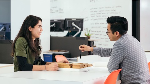 A man and a woman reviewing work at a hightop table. A man and a woman reviewing work at a hightop table.