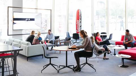People working and meeting in a lobby space next to windows. People working and meeting in a lobby space next to windows.
