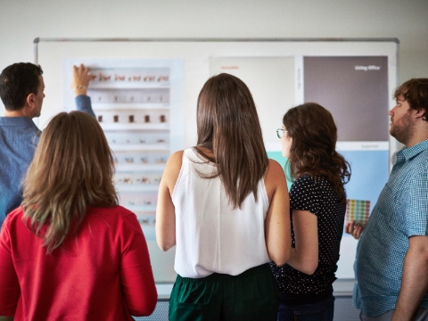 Office employees listen to a presentation from a co-worker. Office employees listen to a presentation from a co-worker.