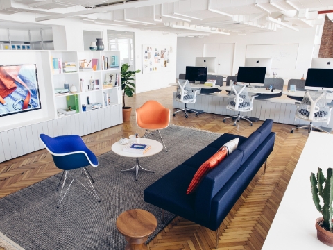 An office loung seating area sits near several workstations in the background. An office loung seating area sits near several workstations in the background.