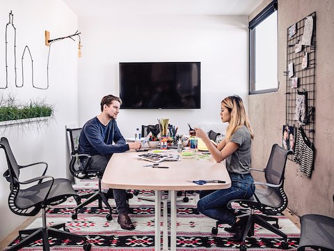 Two people work on a project together at a desk with Setu chairs. Two people work on a project together at a desk with Setu chairs.