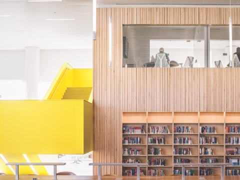 Shelves of library books sit behind benches. Shelves of library books sit behind benches.