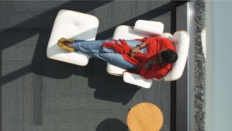 Woman sitting in a window in a White Leather Eames Chair with matching ottoman. Woman sitting in a window in a White Leather Eames Chair with matching ottoman.